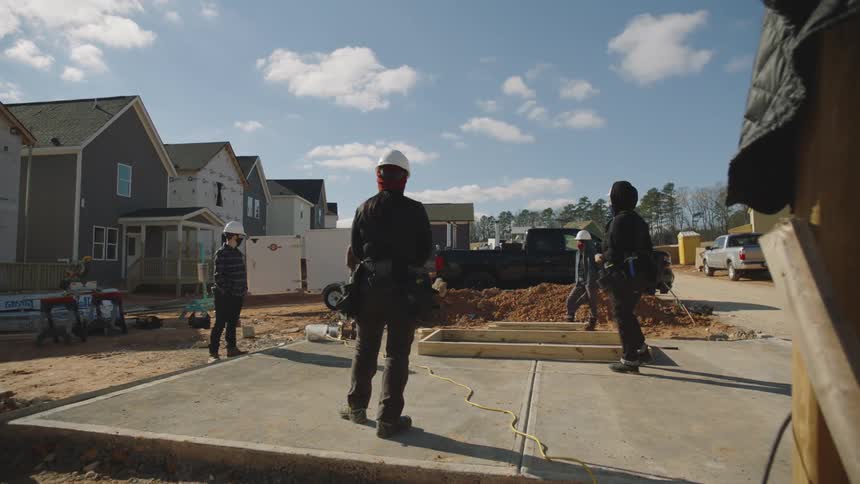 There are three construction workers that are outdoors in the day time