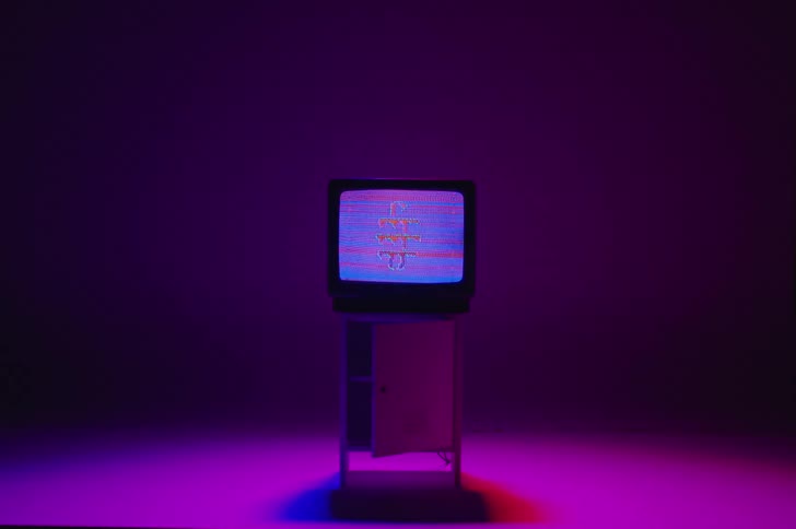 A television sitting on a cabinet displays a blurring distorted image with colorful lights