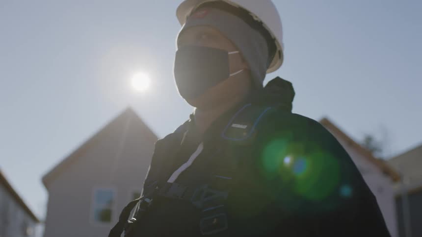 A woman carries a construction cord past a home that is being built