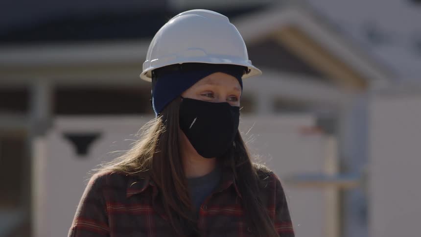 A construction worker chats while outside a house