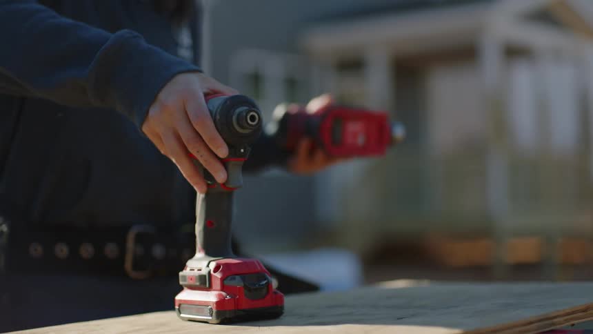 A construction worker puts away drills while working outside a house