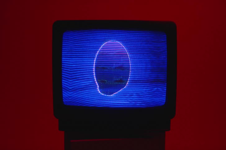 Television display shows flickering image in red lit room