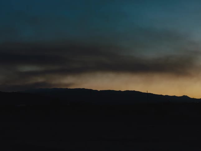 Dark ground and gray clouds contrast with red tint on horizon