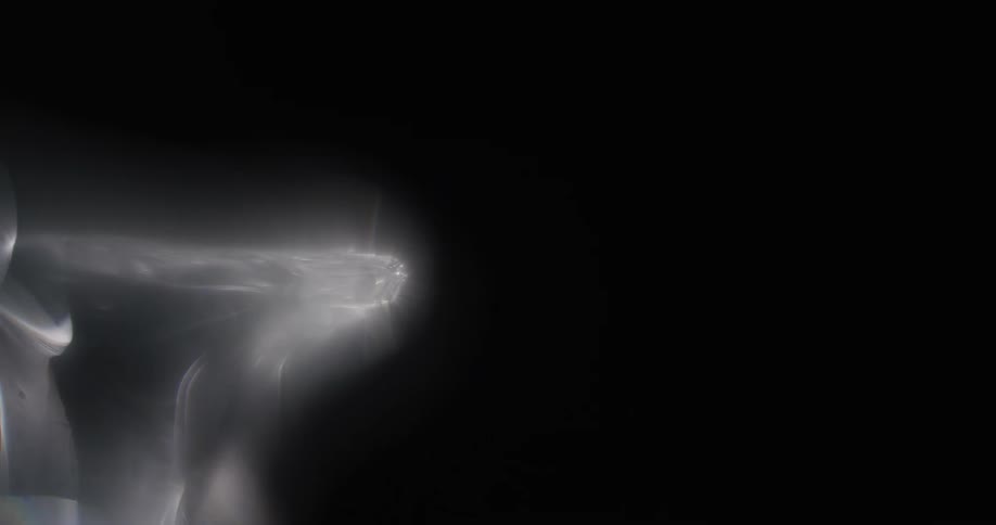 Light shines on a smokey substance as it moves across the darkness
