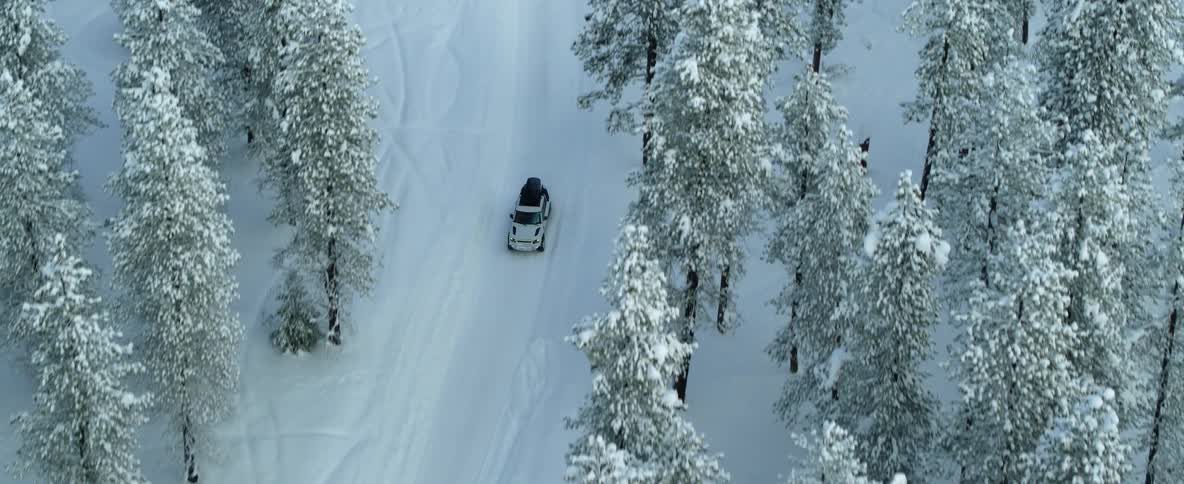 An aerial view of a vehicle driving over a snow covered road