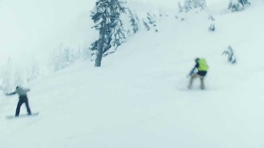 Two snowboarders going over a jump on a snow mountainside