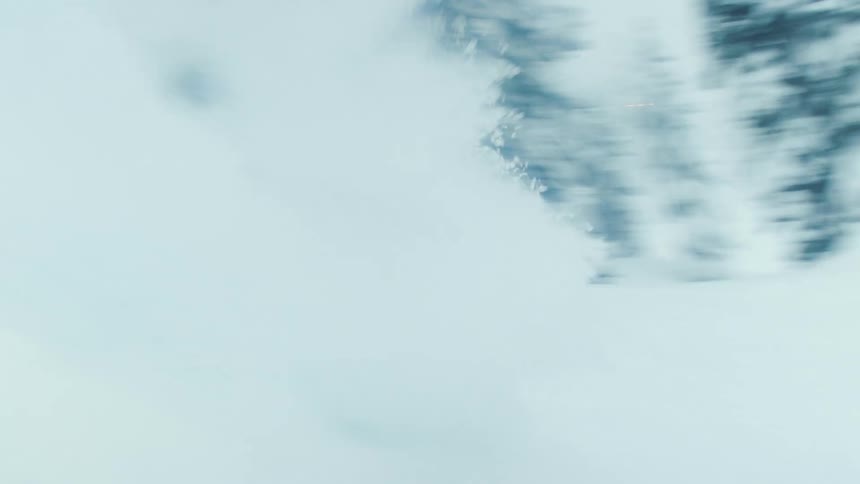 A snowboarder throws up their hands while going down a mountain