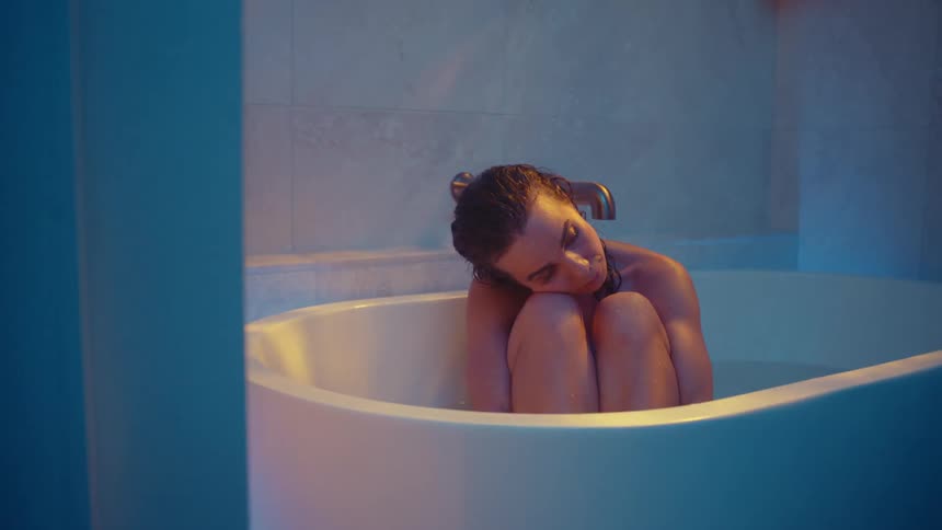 There is a young white woman sitting in the bath tub