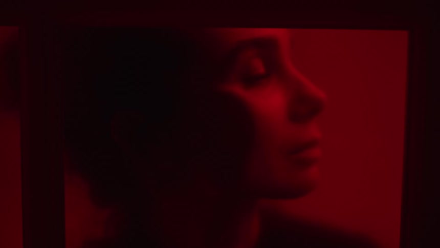 Woman in room lit by red lighting turns her head