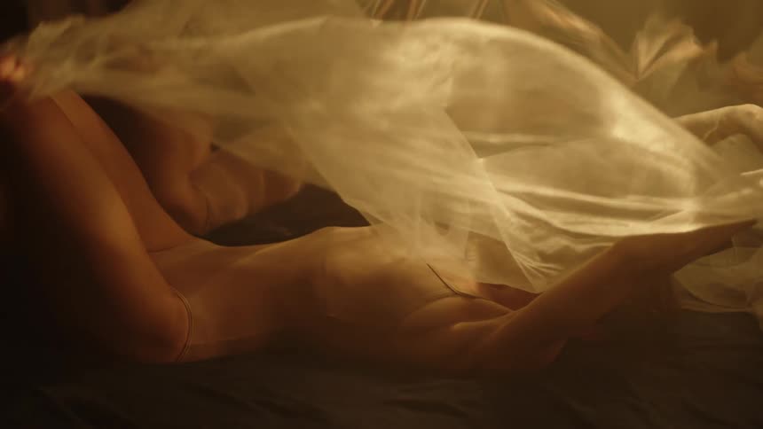 A white cloth falls onto two women lying in a pool