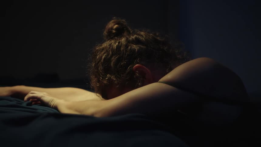 A woman slides off the end of her bed