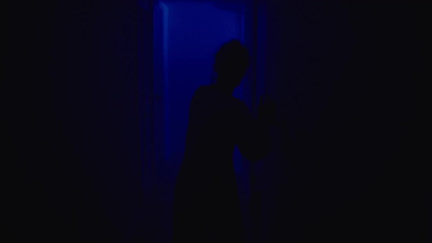 A woman is walking through a hallway during the night time