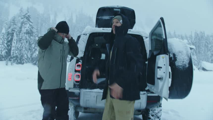 Two men are putting on jackets during the winter time