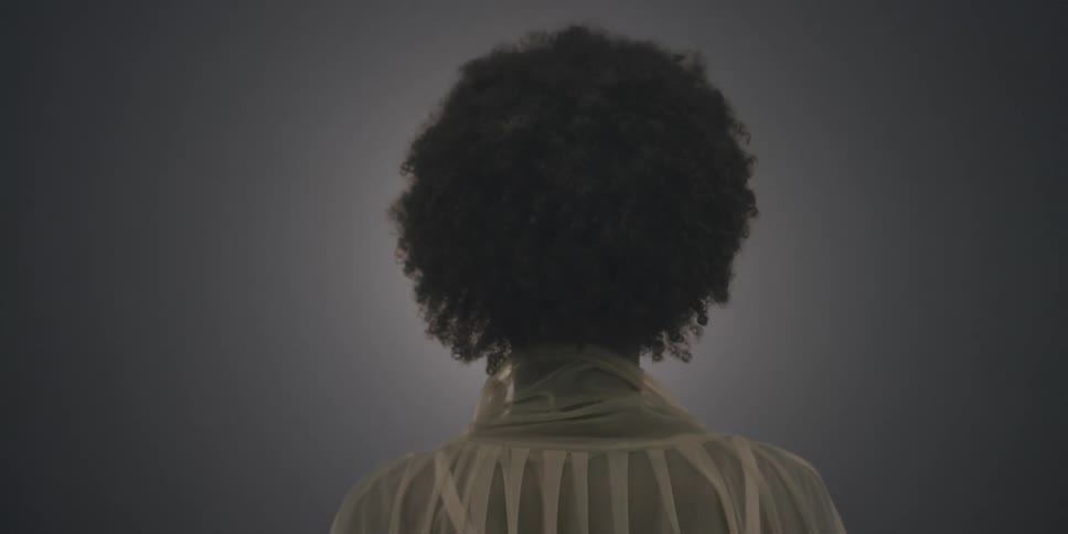 The back of a black woman in sheer top as photographer light flashes