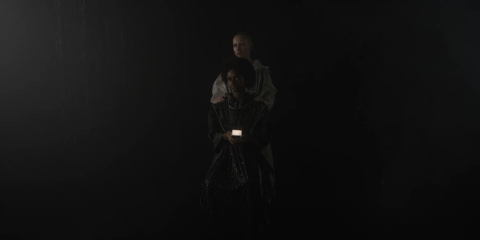 A model stands behind a seated model