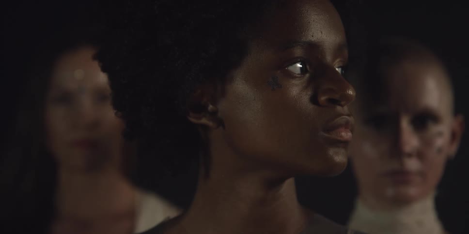 A black woman turns her head while two white women stand still behind her