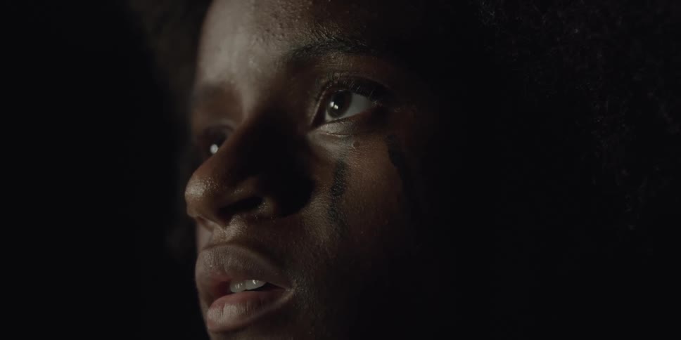 A black woman stares as drops of water fall
