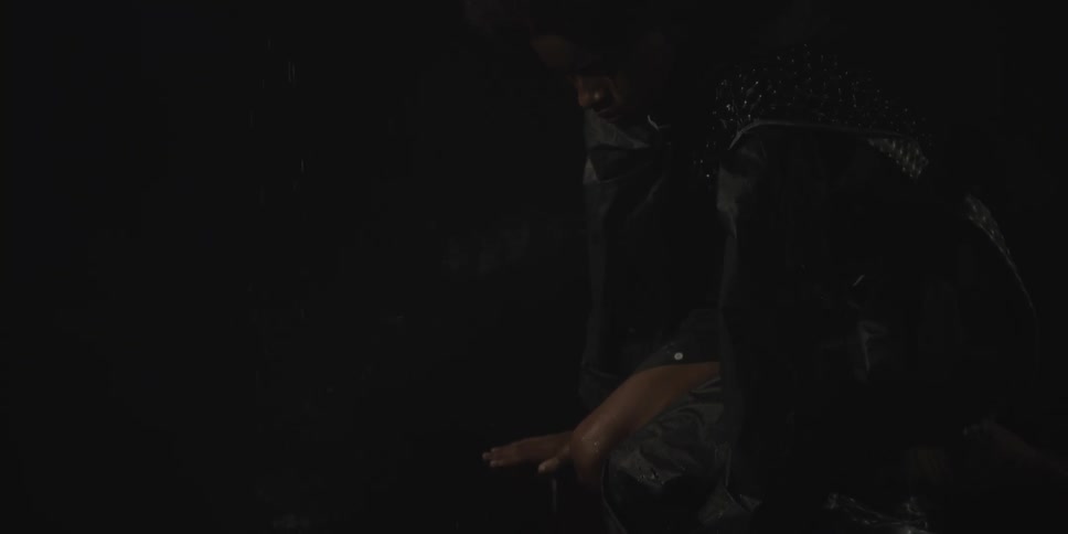 A person bending down and putting their hand out in to the falling rain