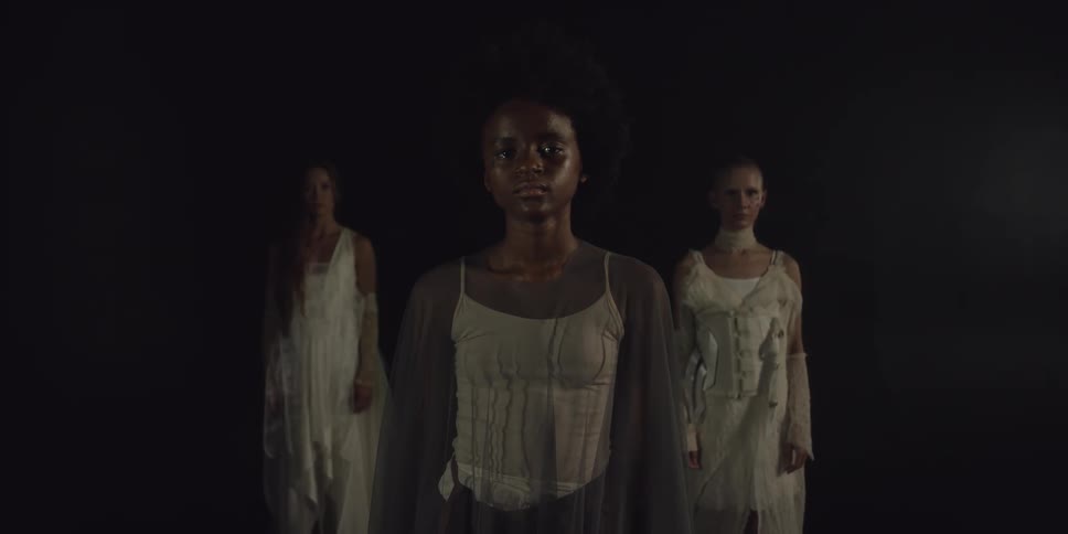 Models in flowy dresses stand in a triangle formation