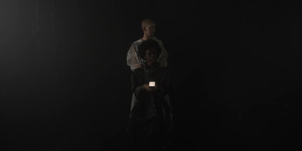 Two women are standing by each other in a dark room