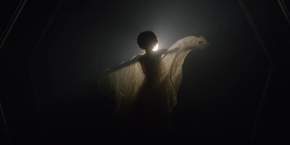 A model dances inlace dress in front of a bright lamp