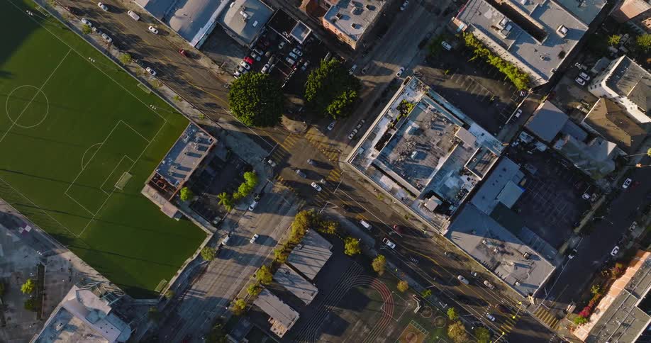 Aerial view of traffic moving through town among buildings and a soccer field