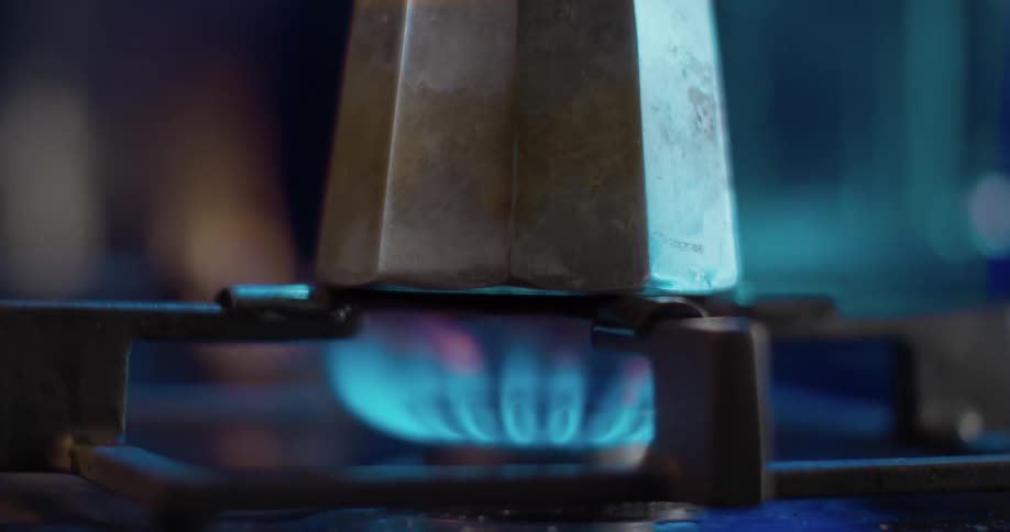 A gas flame ignites and a coffee pot is placed on top of the blue flames