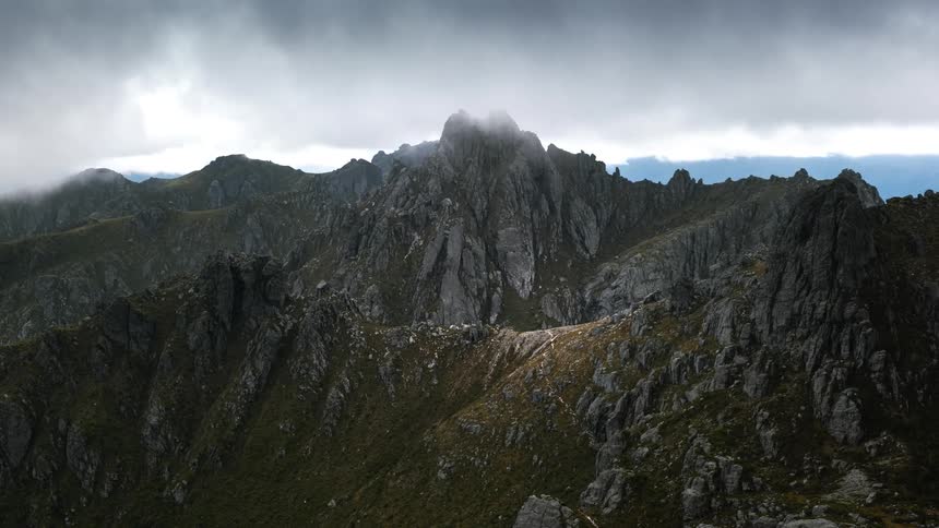 Clouds move over a mountain range with peaks high in the sky
