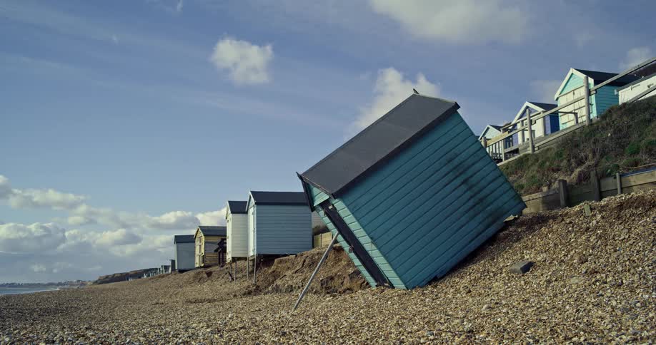Leaning storm damaged beach hut on a pebble beach