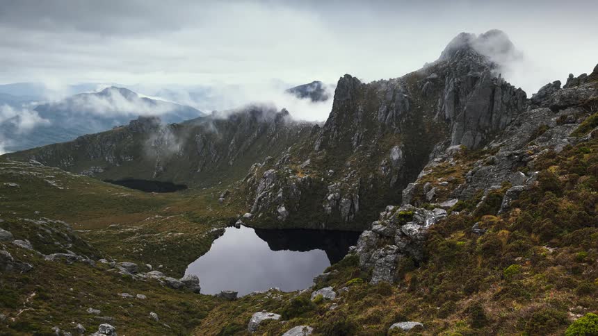 A time lapse shows clouds passing above a rocky mountainous area