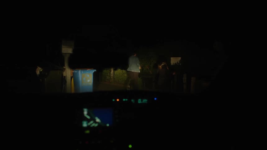Two people running by a car at night