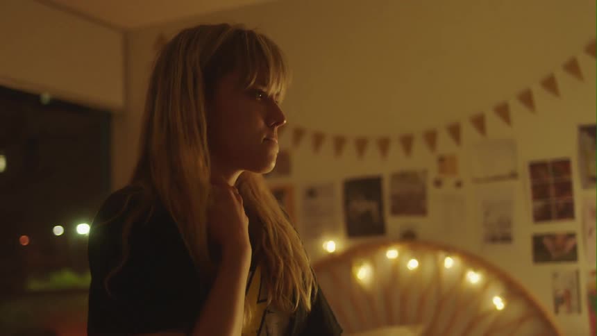 Blonde woman moves phone down from her ear and stands staring