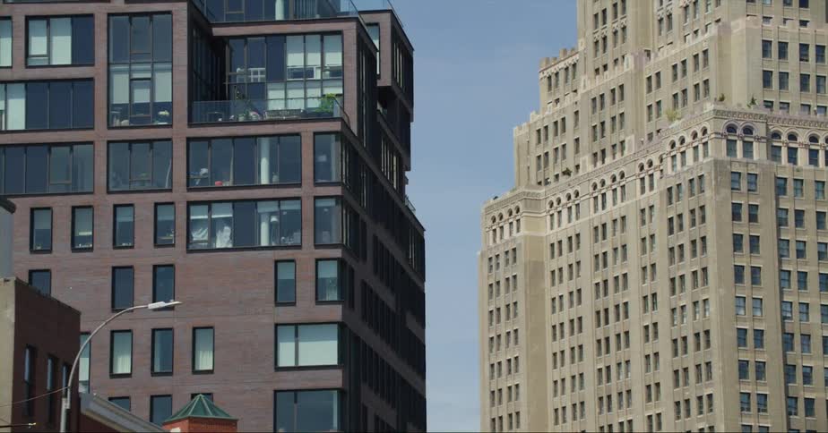 Tall office buildings stand on a downtown street with big windows under a clear sky