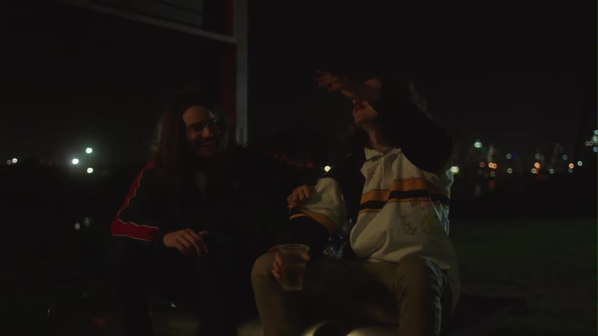 Two friends sitting outside drinking laughing and singing