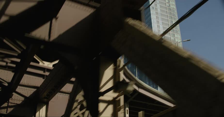 Traveling across a bridge into town a tall building can be seen through the beams