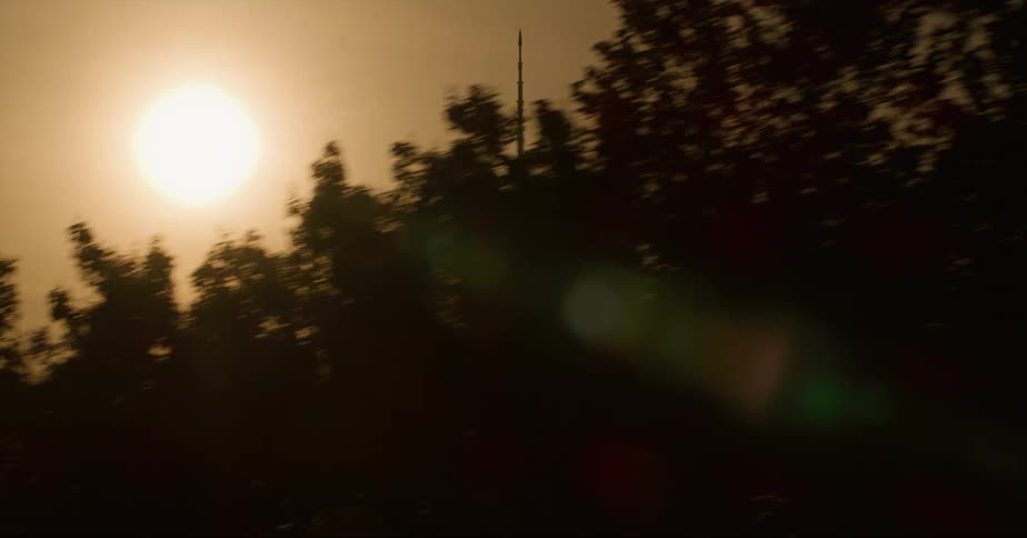 The bright sun in the sky next to a tower