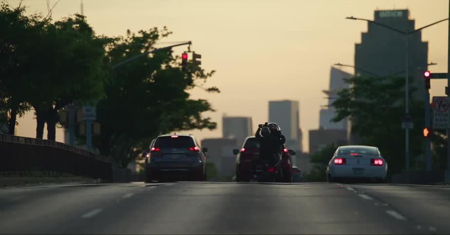 Man riding a motorcycle doing a wheelie on the city street at evening