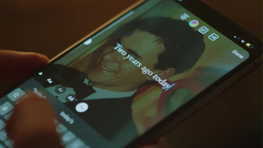 A person texts a message of loss on the photograph of a young man in a tuxedo