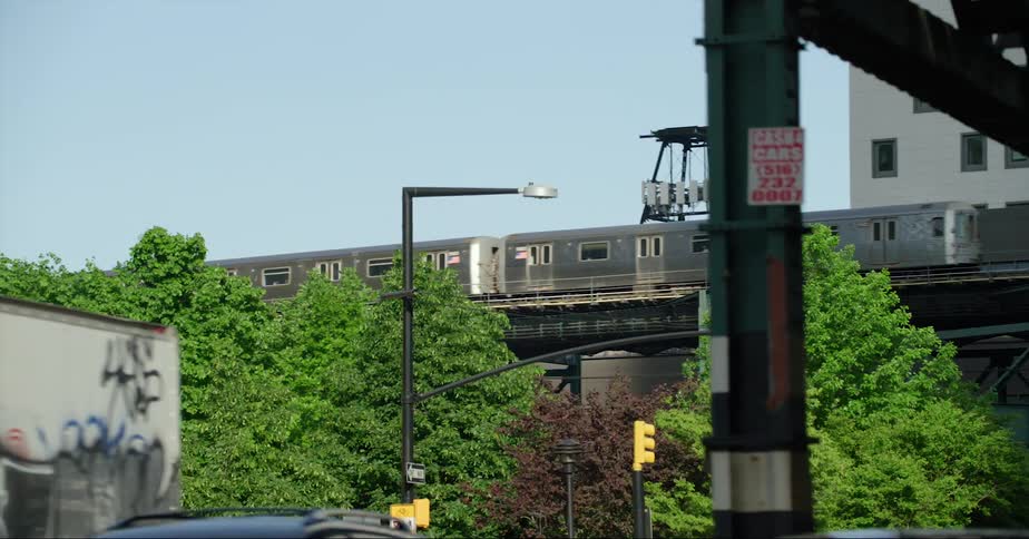 A commuter train passes along some overhead tracks above city traffic