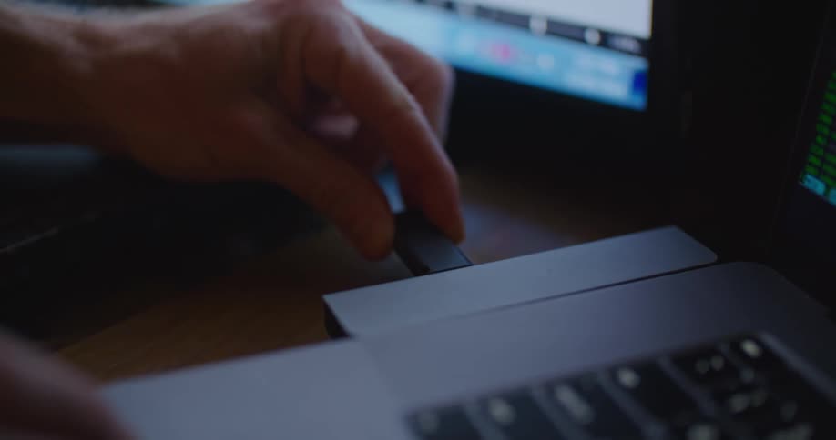 A person sticks a flash drive in a laptop