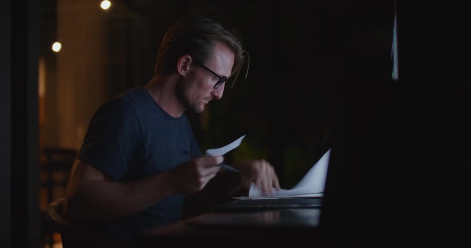 A man takes notes while working on his computer