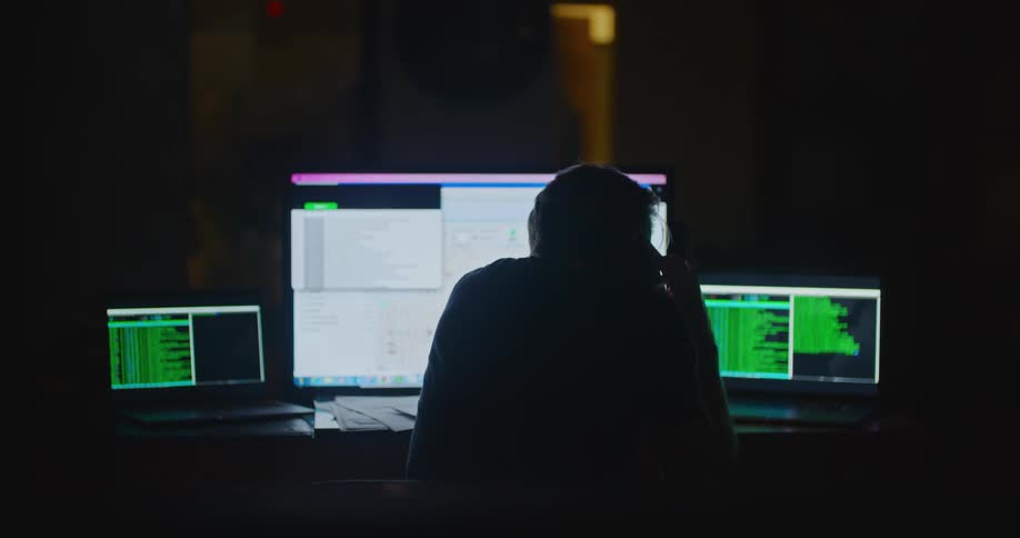 A man talks on the phone while working at his desk