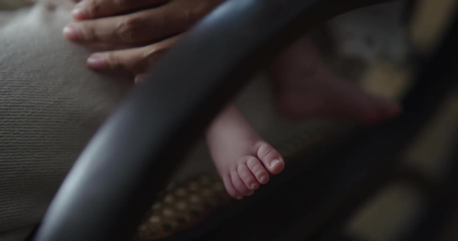 Mother touches babys legs lying in her lap
