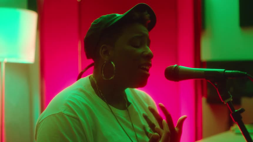 Young woman singing in front of a microphone on a room full of colorful lights
