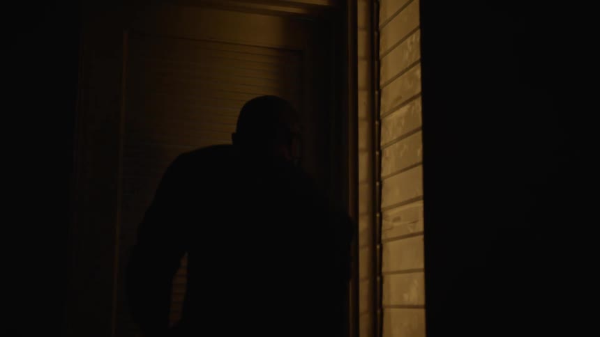 Man with glasses and beard opens door and repairs electric panel in dark room