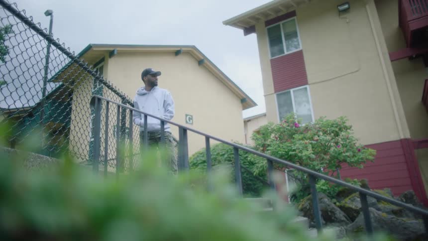 A man stands outside an apartment building