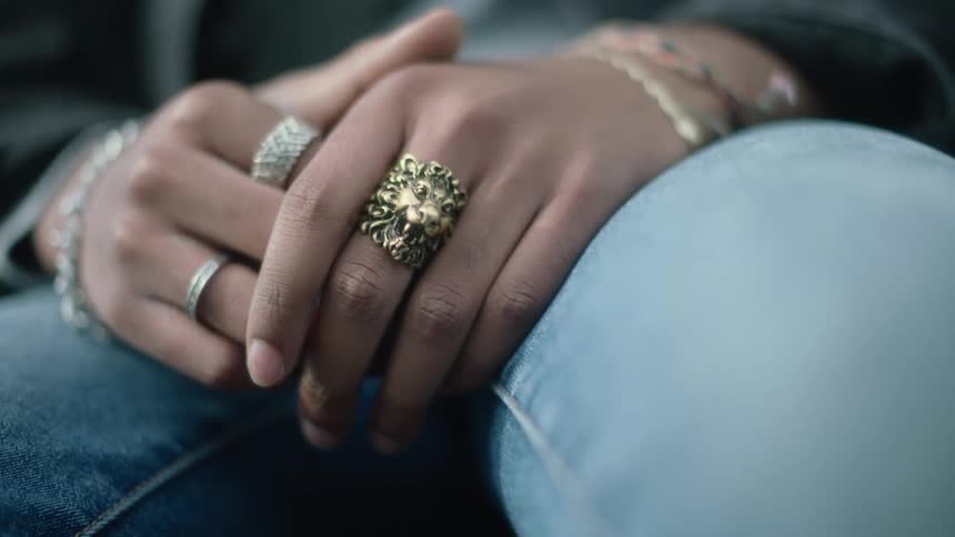 Woman wearing jeans coat and rings sits down