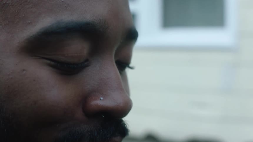 A man laughs while standing outside his house