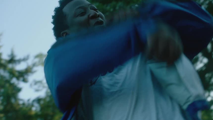 A man is dancing outside as another man claps