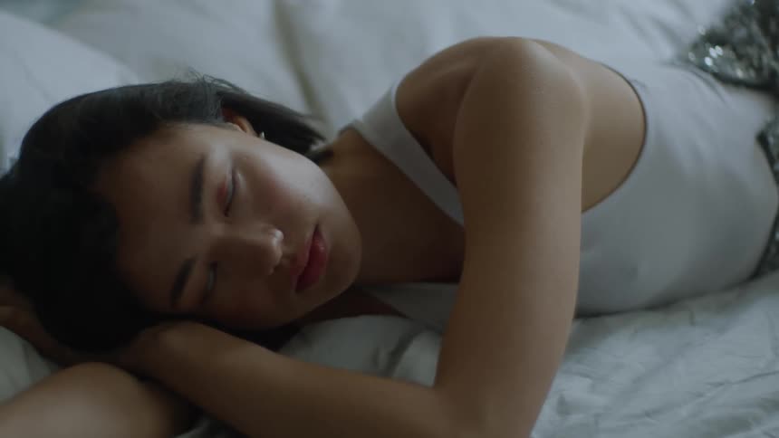 A woman poses while lying on a bed
